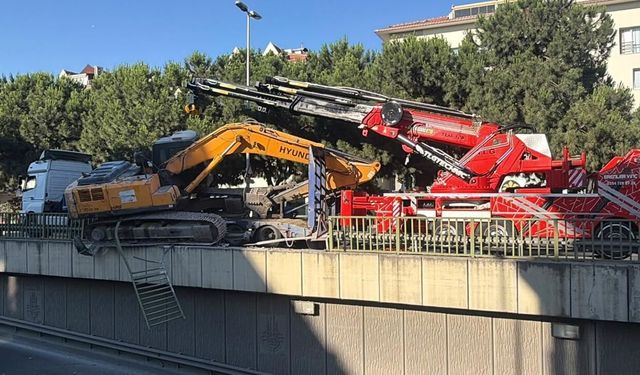 Tırın üzerinden düşen iş makinesi korkuluklarda asılı kaldı